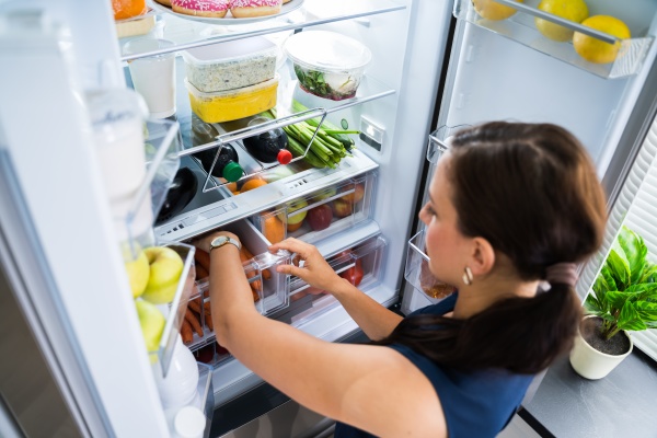 mulheres procurando comida dentro da geladeira