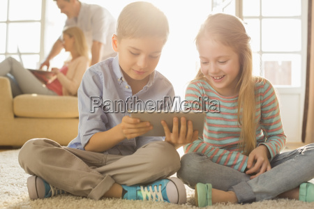 menina bonitinha sentada no chão usando tablet digital tocando a